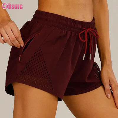 Pantalones cortos deportivos de entrenamiento para mujer al por mayor, transpirables, con corte láser, para correr, con bolsillo lateral con cremallera para calentamiento, patrón sólido